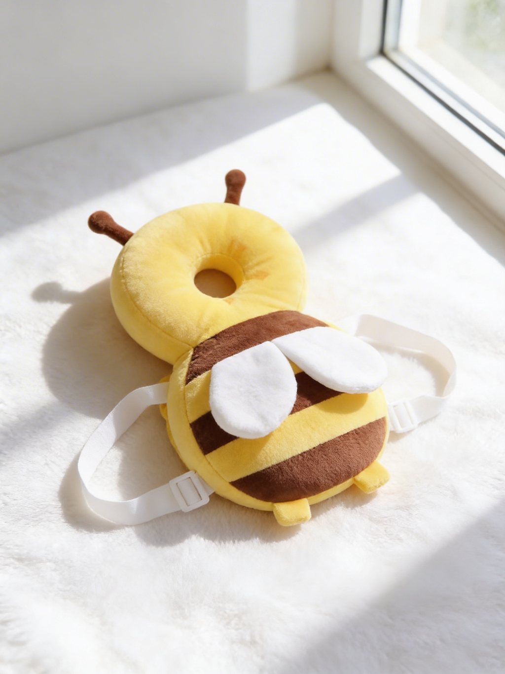 Little Bee head cushion seen from the side on a white blanket